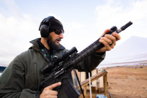 man with ear protection holding a U.S. Arms rifle